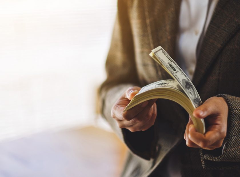 Closeup image of a woman holding and counting American dollar banknotes for money and financial concept