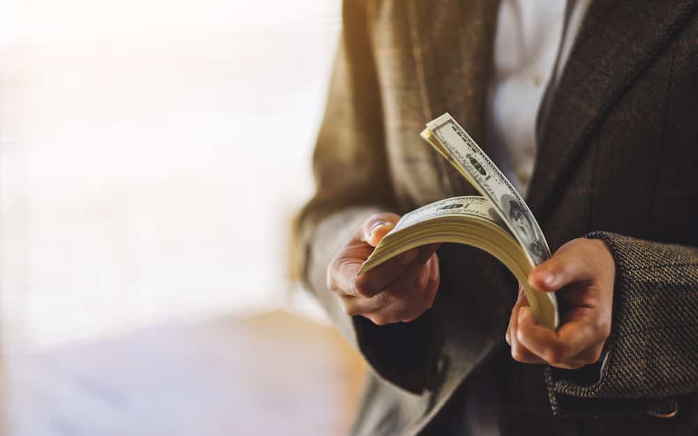 Closeup image of a woman holding and counting American dollar banknotes for money and financial concept