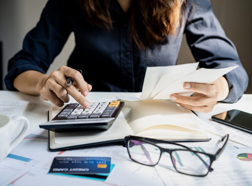 Stressed young woman checking bills, taxes, bank account balance and calculating expenses in the living room at home