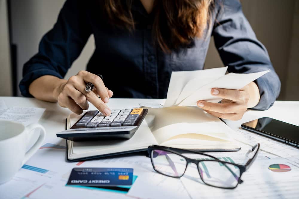 Stressed young woman checking bills, taxes, bank account balance and calculating expenses in the living room at home