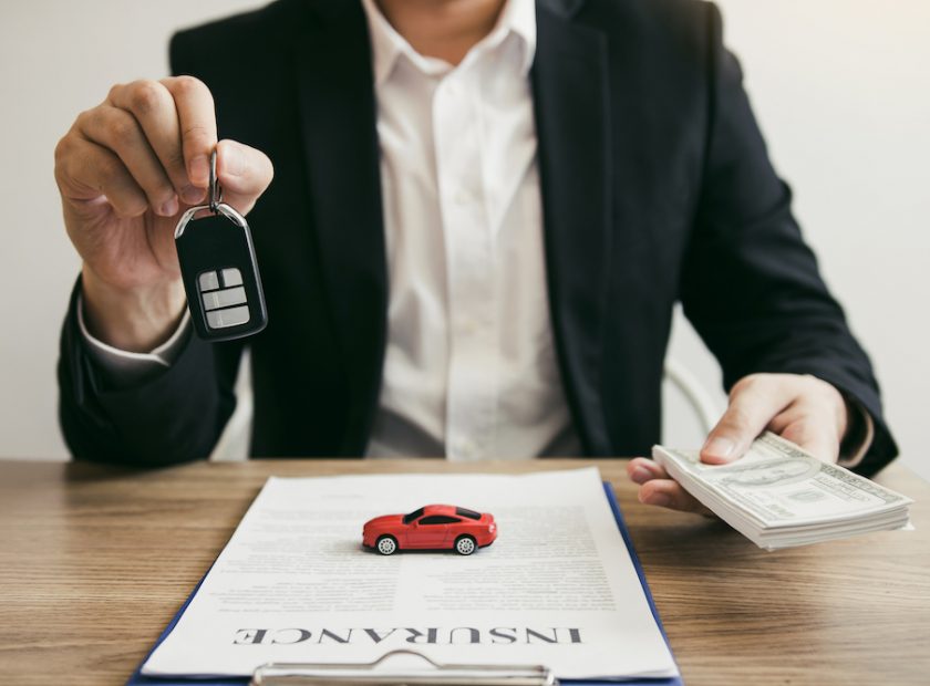 Car salespeople are holding car keys by submitting to new car buyers with car insurance concept.