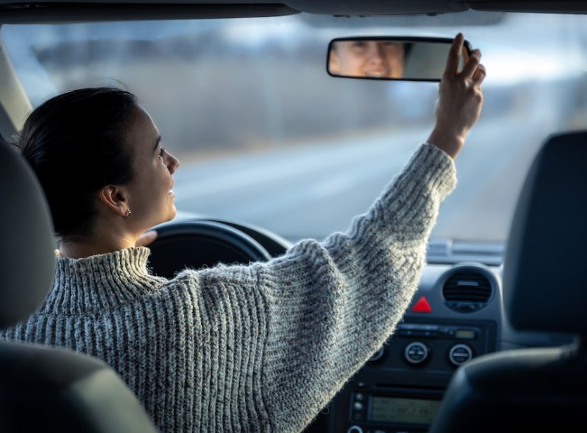 Happy young woman drives a car, inside view.